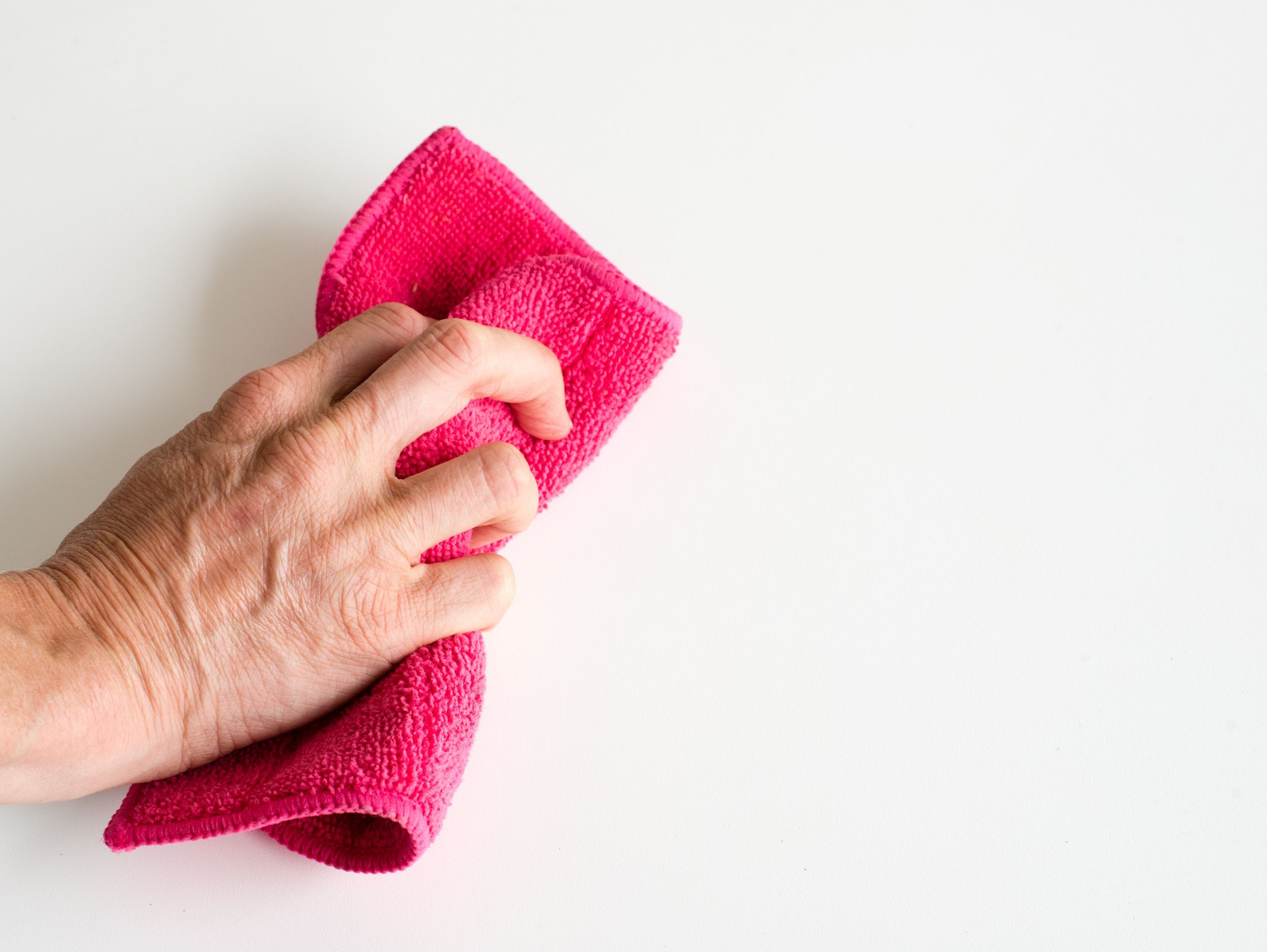 Cropped Hand Cleaning White Wall With Napkin